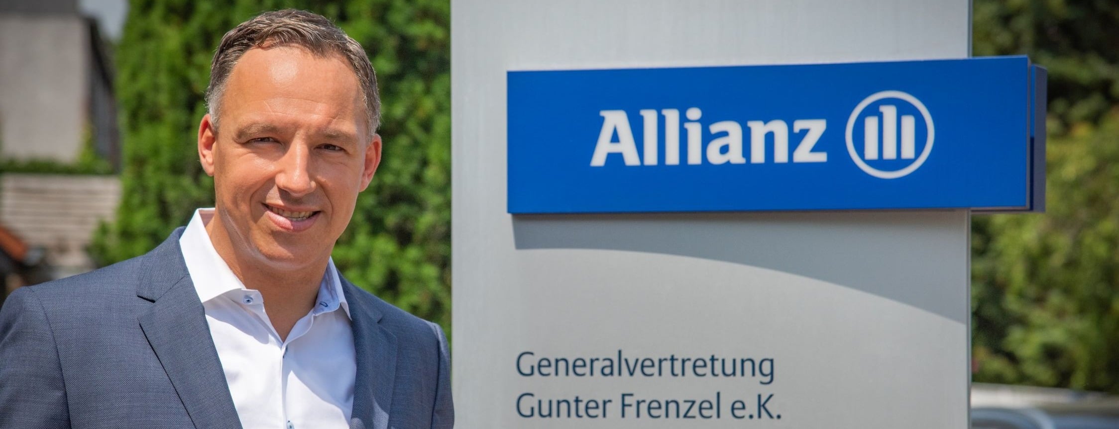 Allianz Versicherung Gunter Frenzel e.K. Inh. Denis Frenzel Bad Homburg - Mann steht neben Allianzschild